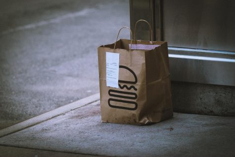 Photo by Jon Tyson on Unsplash. A food delivery sits on a doorstep.
