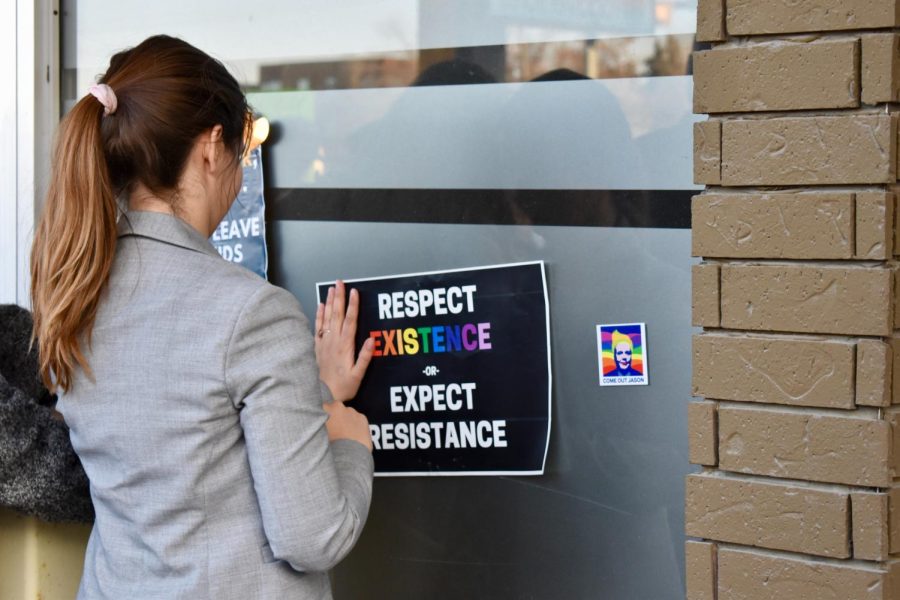 A person posting a paper that says, Respect existence, expect resistence, on a fridge.